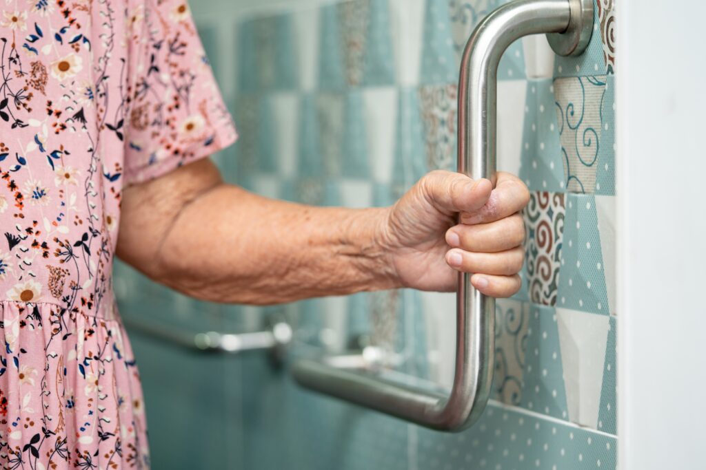 Senior adult using bathroom grab bars installed through NHTD home safety modification program