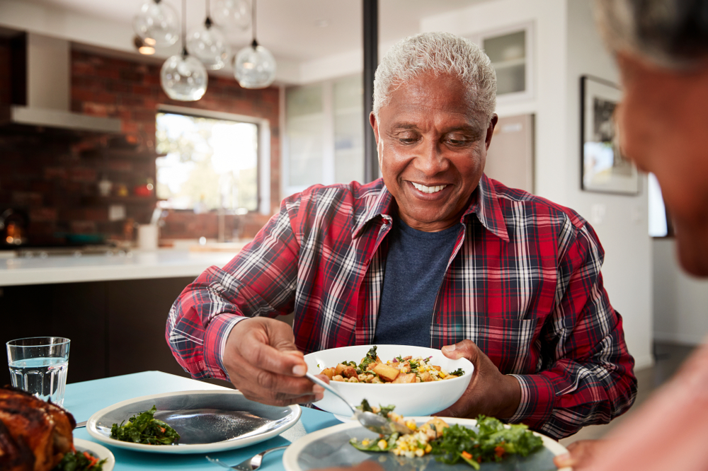 Senior adult preparing a bowl of high-fiber foods including fruits, vegetables, and whole grains to support digestion and heart health after 60.