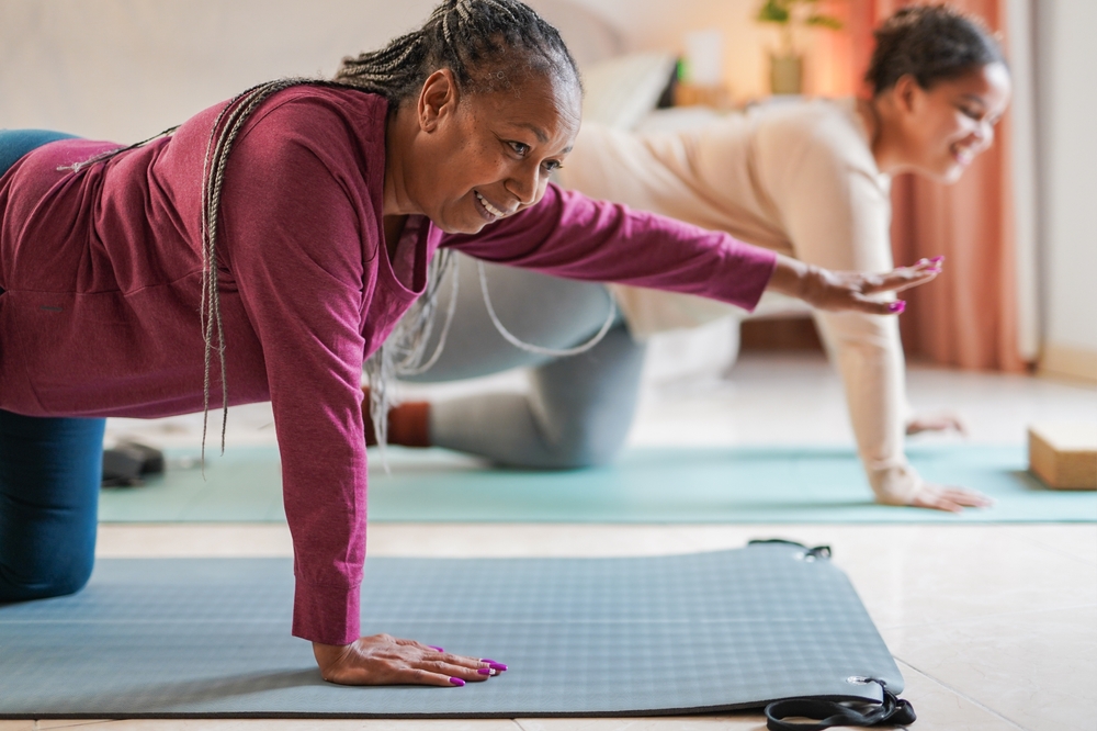 Senior woman practicing gentle yoga with a mat and chair support in a bright living room