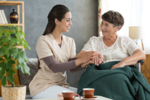 Senior man with Parkinson’s disease doing guided stretching exercises at home with caregiver assistance